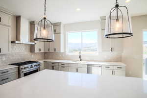 Kitchen featuring decorative backsplash, appliances with stainless steel finishes, wall chimney range hood, and sink