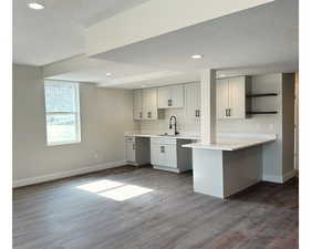 Entertainer's Kitchen featuring a kitchen breakfast bar, kitchen peninsula, dark hardwood / wood-style flooring, a textured ceiling, and sink