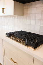 Details featuring white cabinets, backsplash, and stainless steel gas cooktop