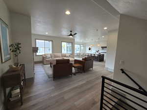 Living room featuring ceiling fan, a textured ceiling, and light wood-type flooring