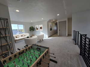 Recreation room with a textured ceiling, a water view, and light colored carpet