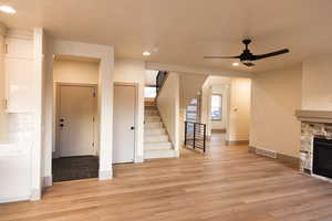 Unfurnished living room with a fireplace, light hardwood / wood-style flooring, and ceiling fan