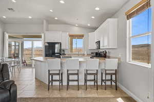 Kitchen featuring black fridge, a healthy amount of sunlight, and white cabinets