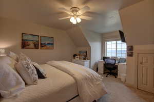 Bedroom with light carpet, ceiling fan, and lofted ceiling