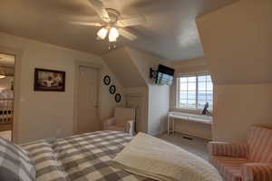 Carpeted bedroom featuring ceiling fan and lofted ceiling