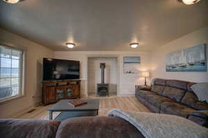 Living room with hardwood / wood-style flooring, a heating stove, and a textured ceiling