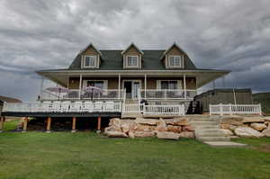 Rear view of house featuring covered porch and a lawn