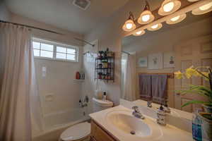 Full bathroom featuring shower / bathtub combination with curtain, oversized vanity, and toilet