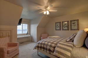 Carpeted bedroom with ceiling fan and lofted ceiling