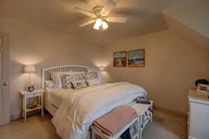 Carpeted bedroom with ceiling fan and vaulted ceiling