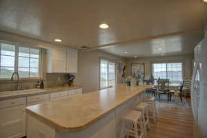 Kitchen featuring a wealth of natural light, sink, and white cabinetry