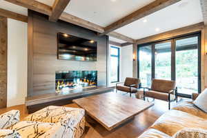 Living room featuring beam ceiling, a multi sided fireplace, and hardwood / wood-style flooring