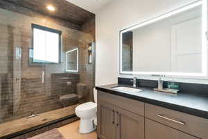 Bathroom with a shower with shower door, toilet, and vanity