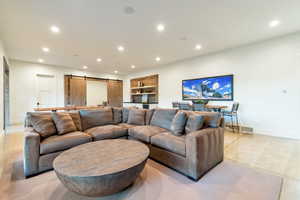 Living room featuring a barn door, built in features, and light tile floors