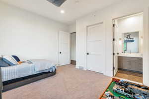 Carpeted bedroom featuring sink and ensuite bathroom