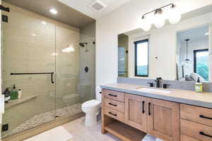 Bathroom with tile floors, a wealth of natural light, vanity, and toilet