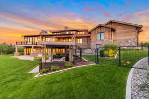 Back house at dusk with a yard, a balcony, a patio area, and an outdoor hangout area