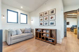 Sitting room featuring lofted ceiling with beams, light hardwood / wood-style floors, and a barn door