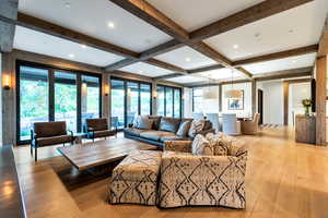 Living room with a wealth of natural light, beamed ceiling, and light wood-type flooring