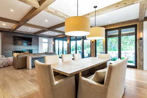 Dining area with beamed ceiling, coffered ceiling, and light hardwood / wood-style floors