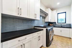 Washroom featuring washing machine and dryer, sink, and cabinets