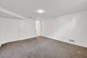 Empty room featuring dark carpet and a textured ceiling