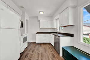 Kitchen with stainless steel appliances, hardwood / wood-style floors, white cabinets, and sink