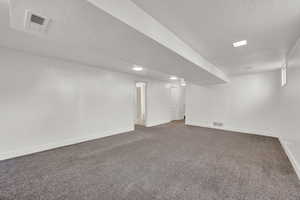 Basement featuring a textured ceiling and dark carpet