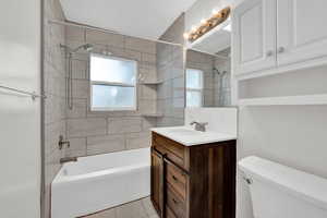 Full bathroom with tile flooring, tiled shower / bath combo, vanity, and toilet