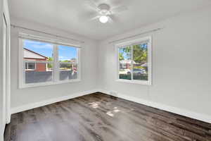 Spare room featuring dark wood-type flooring and ceiling fan