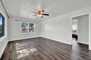 Unfurnished room with plenty of natural light, ceiling fan, and dark hardwood / wood-style flooring