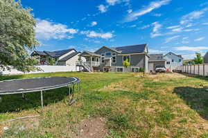 Back of house featuring a yard, a trampoline, and solar panels