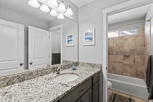 Full bathroom featuring tiled shower / bath combo, tile flooring, toilet, and large vanity