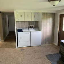 Clothes washing area featuring cabinets, washer and clothes dryer, washer hookup, a wood stove, and carpet