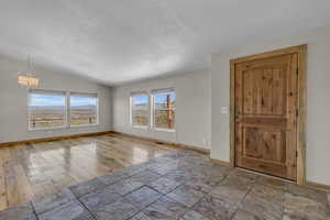 Entrance foyer with a notable chandelier, tile flooring, a textured ceiling, and lofted ceiling