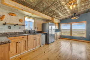 Kitchen featuring stainless steel appliances, sink, light hardwood / wood-style floors, and lofted ceiling