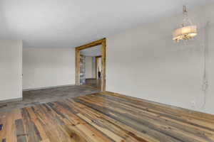 Empty room with a notable chandelier, lofted ceiling, and hardwood / wood-style floors