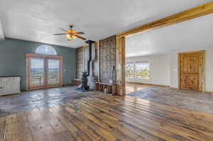 Unfurnished living room featuring ceiling fan, a textured ceiling, a wood stove, and tile floors