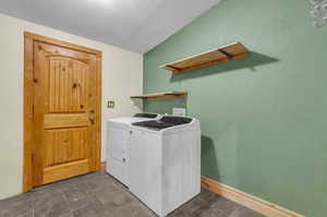 Washroom featuring washer and clothes dryer, dark tile floors, and a textured ceiling