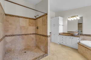 Bathroom with tile flooring, independent shower and bath, and vanity