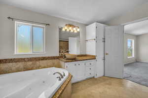 Bathroom with tile floors, a textured ceiling, lofted ceiling, and large vanity