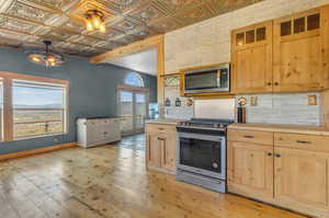 Kitchen with decorative light fixtures, a healthy amount of sunlight, light hardwood / wood-style flooring, and stainless steel appliances