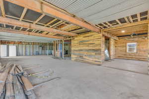 Misc room featuring a wealth of natural light, wood walls, and concrete flooring