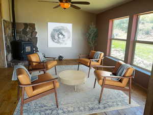 Living room featuring hardwood / wood-style floors, ceiling fan, and a wood stove