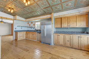 Kitchen featuring vaulted ceiling, light brown cabinetry, light hardwood / wood-style floors, stainless steel appliances, and ceiling fan