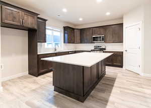 Kitchen with appliances with stainless steel finishes, a center island, decorative backsplash, and light wood-type flooring