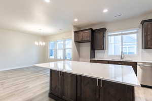 Kitchen featuring sink, light hardwood / wood-style floors, decorative backsplash, a center island, and dishwasher