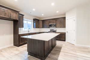 Kitchen featuring stainless steel appliances, a kitchen island, tasteful backsplash, and light wood-type flooring