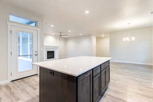 Kitchen featuring light hardwood / wood-style floors, decorative light fixtures, a center island, and ceiling fan with notable chandelier