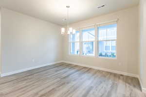 Spare room featuring a chandelier and hardwood / wood-style flooring